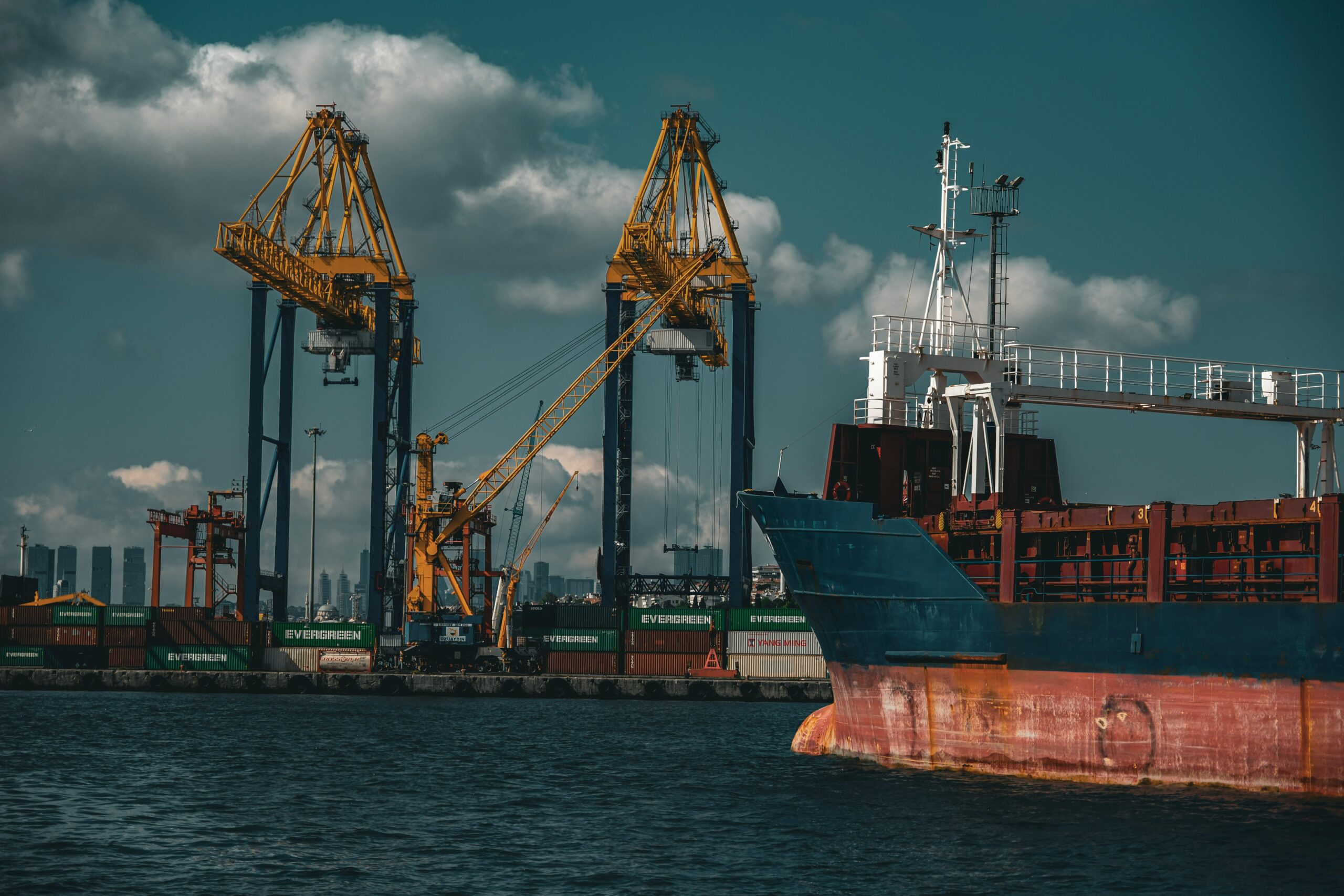 Cargo ship and cranes at a bustling port in Istanbul, showcasing industrial logistics.